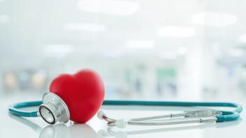 Stethoscope and a heart figurine laying on a table.