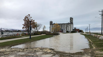 The Collingwood Terminals on the waterfront, with a large puddle of water in the foreground on a cloudy day.