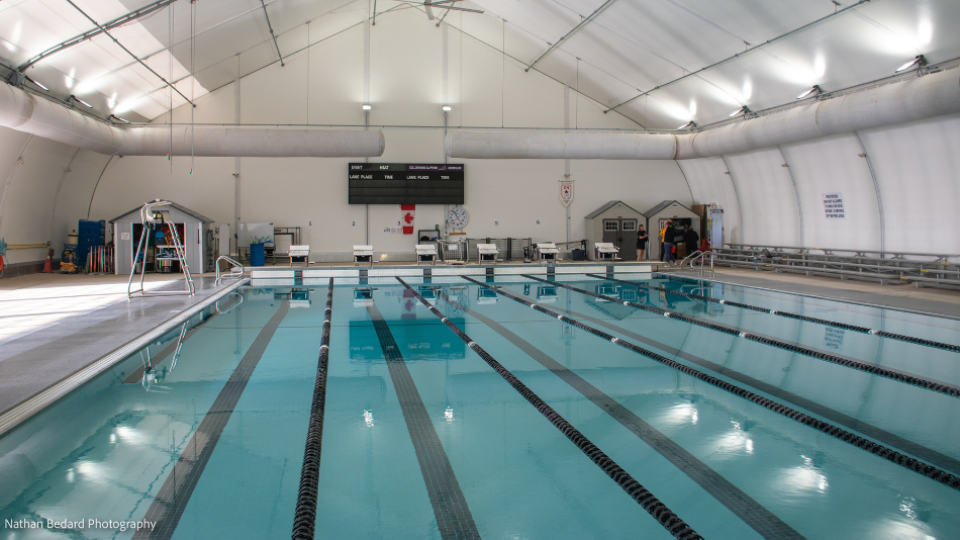 An indoor swimming pool with multiple lanes marked by black ropes and buoys.