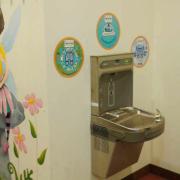 Metal water fountain on a wall decorated with art