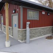 Grey water fountain against the side of an outdoor public washroom