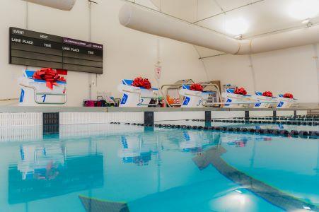 Photo of diving blocks at a swimming pool with giant red ribbons atop each
