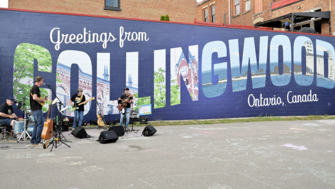 Band playing in front of the Greeting from Collingwood mural