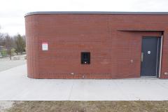 A rectangular brick building with a black door on the right