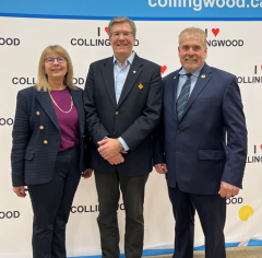 Three people standing in front of a I Love Collingwood banner.