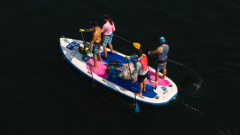 4 people on a stand up paddle board with garbage they collected