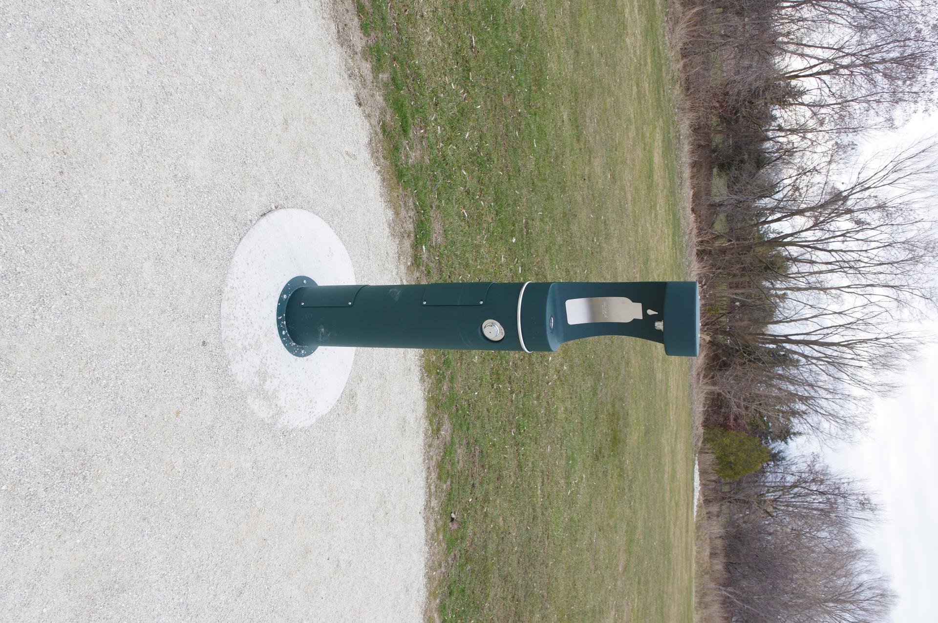 Tall, narrow and dark green water fountain in a park