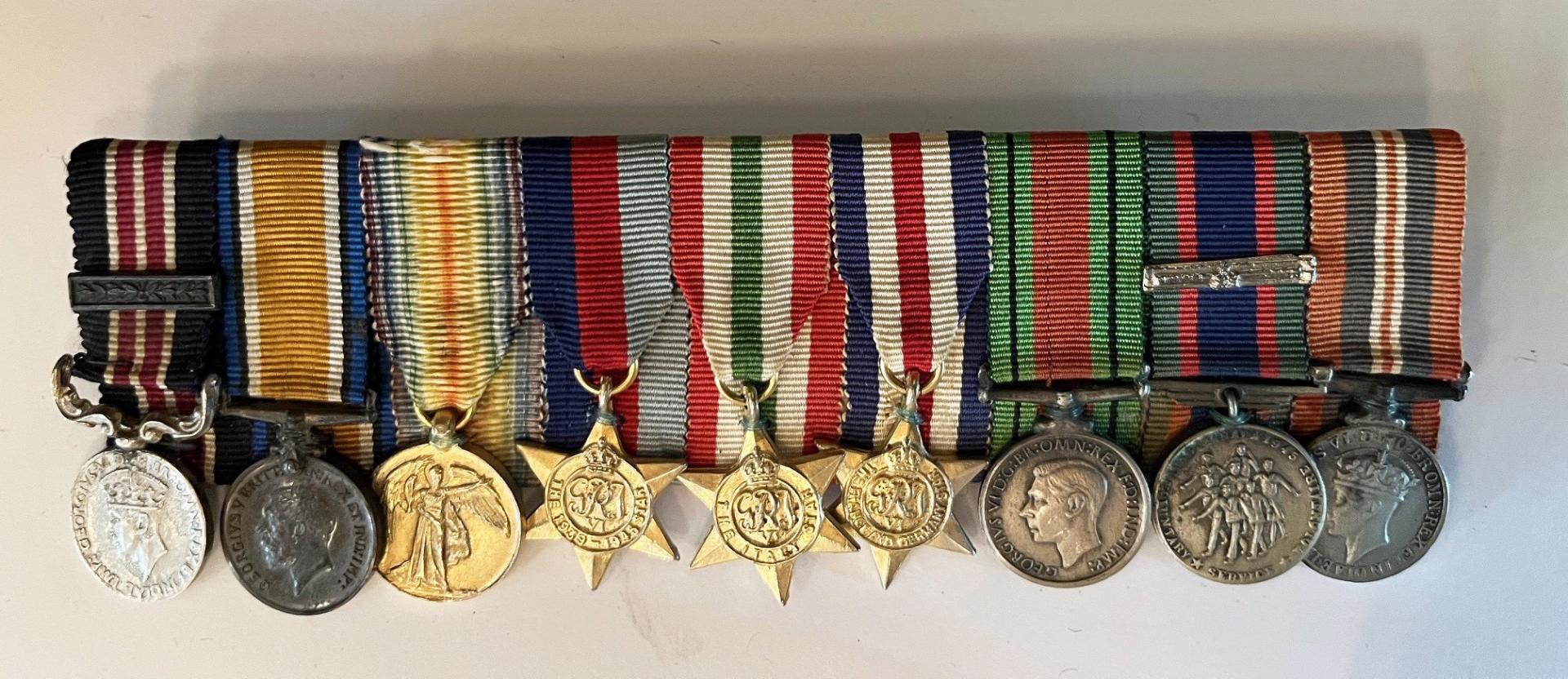 Row of military medals with coloured ribbons attached to them.